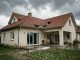 Maison individuelle après un orage de grêle, avec des tuiles et une gouttière visibles sous un ciel chargé.