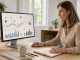 Une dirigeante de petite entreprise consulte des graphiques financiers abstraits sur un ordinateur dans un bureau moderne et lumineux.